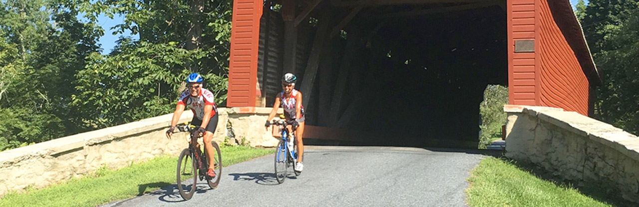 Bicyclists crossing a covered bridge in Berks County